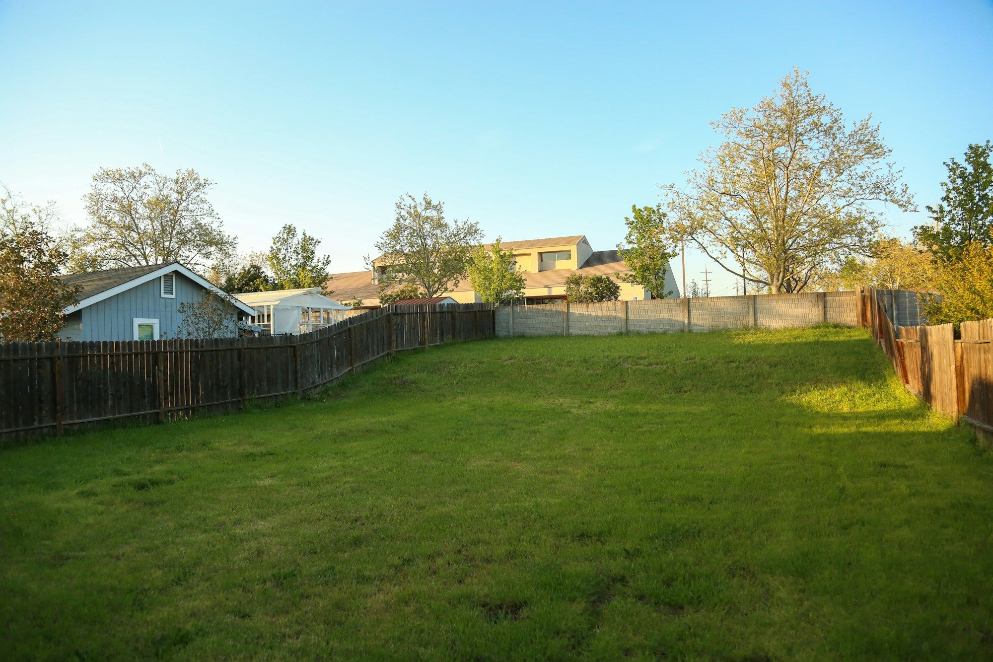Wood privacy fence running around a wide, freshly mowed backyard