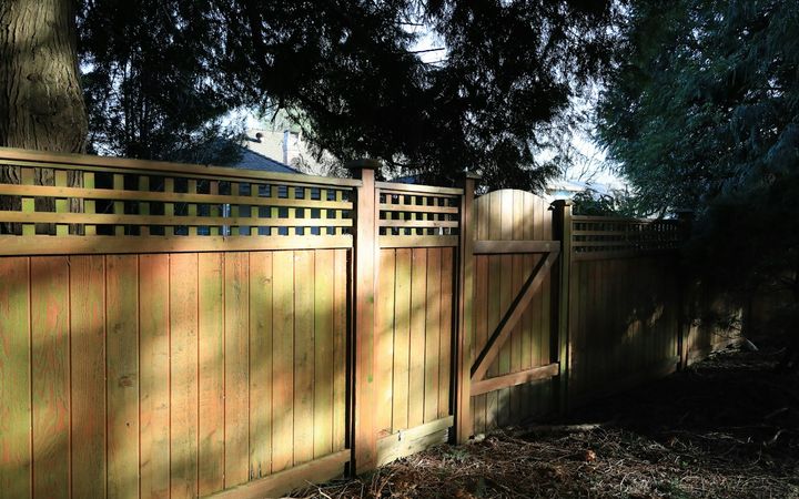 Tall board privacy fence with a lattice top and a matching gate