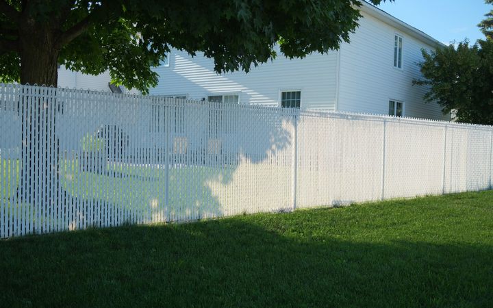White vinyl privacy fence enclosing the backyard of a two-story house